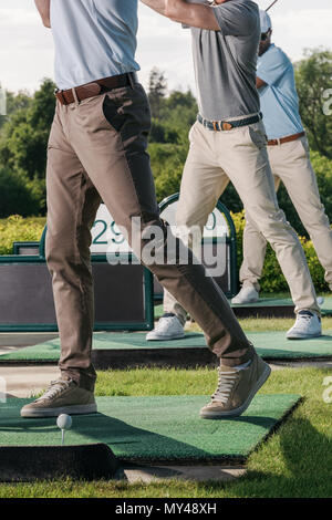 partial view of group of men playing golf together at golf course Stock Photo