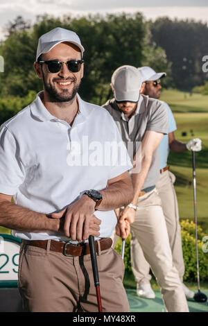 portrait of smiling golfer looking at camera while men playing golf Stock Photo