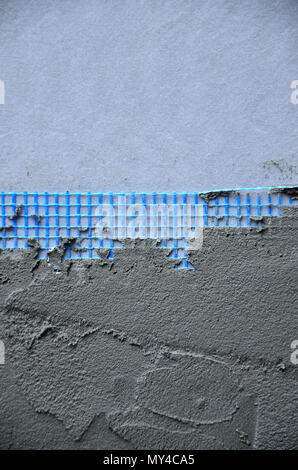 The texture of the wall, covered with gray foam polystyrene plates, covered with a blue reinforcing mesh and covered with a mixture for gluing it. Sta Stock Photo