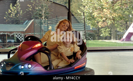 Young mother with her daughter drive on bumper cars Stock Photo