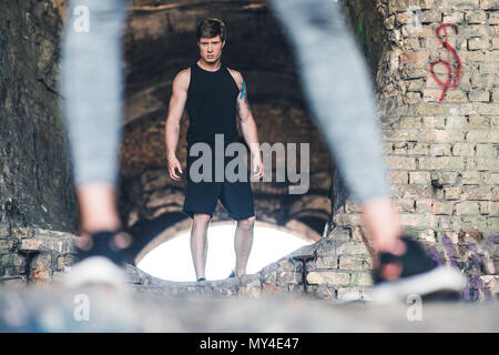 selective focus of young man in sportswear looking at camera while standing on ruins Stock Photo