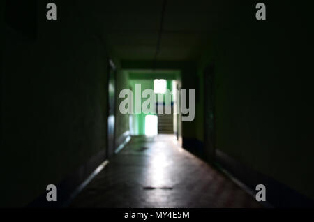 The blurred image of gloomy corridor of a neglected public building. Defocused picture of a public space in a poor residential high-rise building Stock Photo