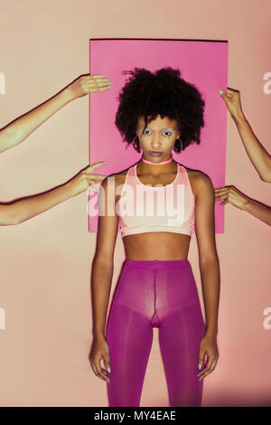 afro 80s girl in pink clothes posing with pink paper behind Stock Photo