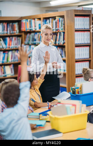 happy young teacher giving lesson to kids in library Stock Photo