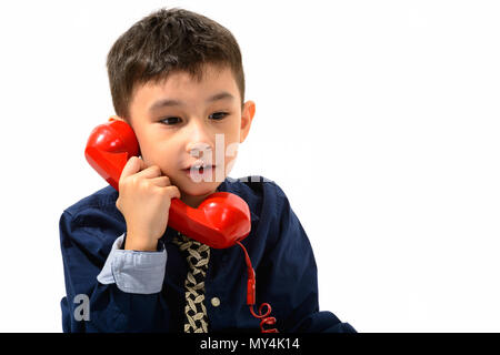 Studio shot of cute boy talking on old telephone and looking dow Stock Photo