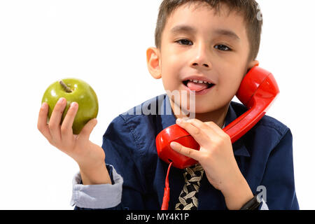 Cute boy sticking tongue out while holding green apple and talki Stock Photo