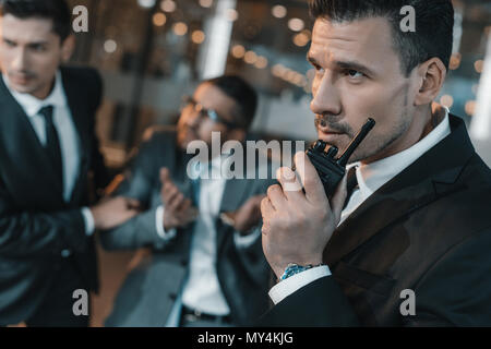 security guard talking by portable radio about male suspect Stock Photo