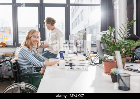 happy incapacitated person in wheelchair working at modern office