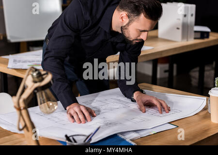 handsome architect looking at blueprints on table Stock Photo