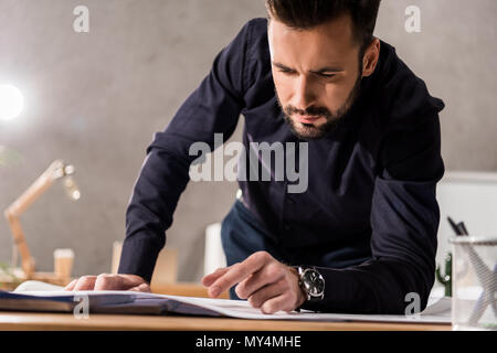 handsome architect looking at blueprints on table Stock Photo