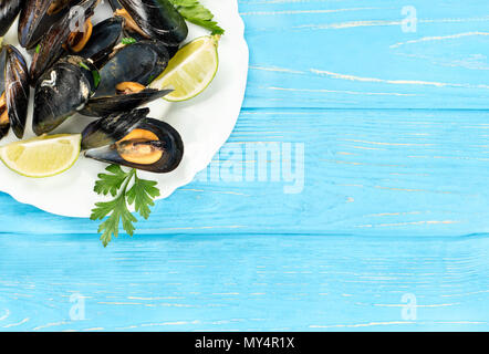 Part of a white plate with cooked mussels on a blank wooden background Stock Photo