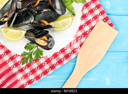 Plate with mussels, lime and parsley on a towel and table, top view Stock Photo