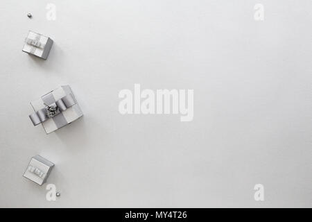 Three silver gift boxes on chromium-plated festive background.   Minimalism, High tech style. Monochrome color Holiday card with presents. Top view Stock Photo