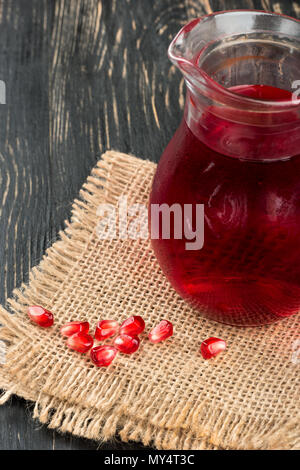 Fresh pomegranate juice with beans on sackcloth and table Stock Photo