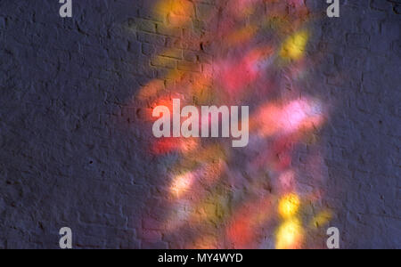 extreme multicolored light reflected in a church, light reflections through a colorful window on a white brick wall in a church Stock Photo