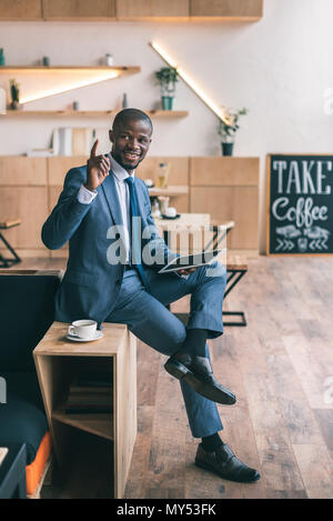 handsome african american businessman having idea and using digital tablet during coffee break in cafe Stock Photo