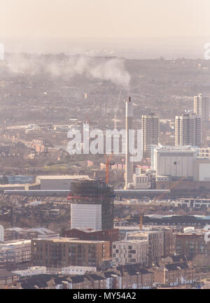 London, England, UK - February 27, 2015: A SouthEastern commuter train passes the chimney of the South East London Combined Heat and Power plant in Be Stock Photo