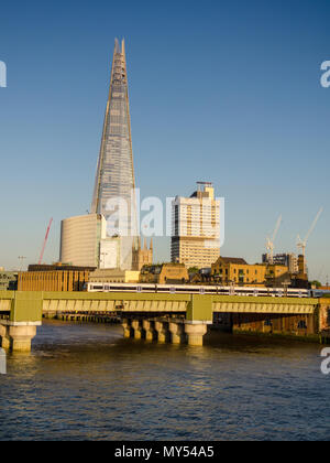 London, England, UK - June 10, 2015: A SouthEastern commuter train crosses the River Thames into London Cannon Street railway station with a backdrop  Stock Photo