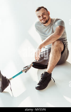 smiling young man with leg prosthesis looking at camera isolated on white Stock Photo