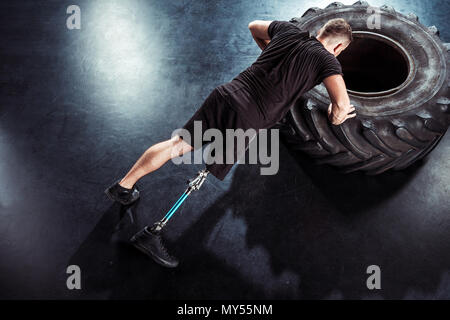 overhead view of  sportsman with leg prosthesis doing push ups on tire Stock Photo