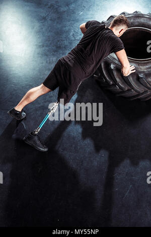 overhead view of  sportsman with leg prosthesis doing push ups on tire Stock Photo