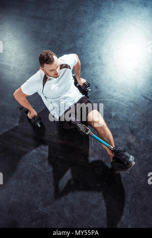 overhead view of man with leg prosthesis doing push ups with dumbbells Stock Photo