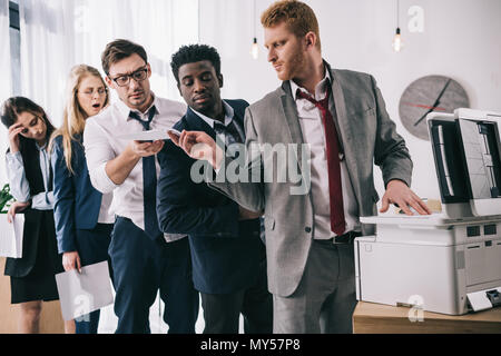 group of businesspeople standing in queue for copier at office Stock Photo
