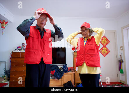 Qingdao, China's Shandong Province. 5th June, 2018. Jiang Shifa (L) and his wife Lian Shifang, wear volunteer uniforms at home in Qingdao, east China's Shandong Province, June 5, 2018. Jiang, 74 years old and his wife, 72 years old, have been volunteers for over ten years after retired from work. The couple feel thrilled to be volunteers for the upcoming SCO Qingdao Summit ten years after they served as volunteers for the Beijing 2008 Olympic Games Sailing event in Qingdao. Credit: Jiang Kehong/Xinhua/Alamy Live News Stock Photo