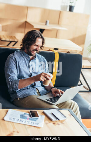 happy bearded man drinking coffee and using laptop Stock Photo