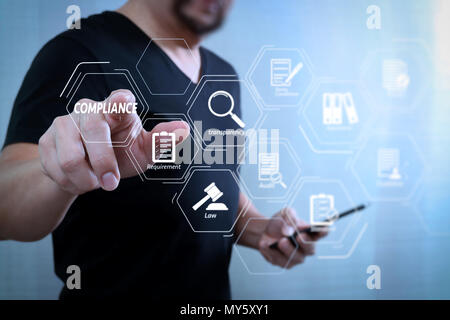 Compliance Virtual Diagram for regulations, law, standards, requirements and audit.Designer hand pressing an imaginary button,holding smart phone,digi Stock Photo