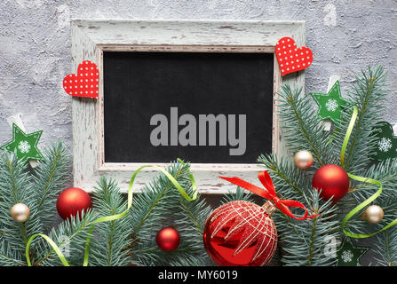 Red and green Christmas decorations: fir twigs, berries and Christmas baubles on gray concrete background, text space Stock Photo
