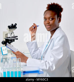 African scientist, medical or or graduate student. Bright, confident young woman in lab coat inerrupted her work to look at the viewer. Stock Photo