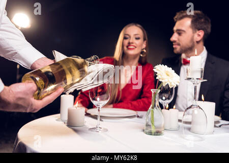 waiter pouring wine while couple having romantic date in restaurant on valentines day Stock Photo