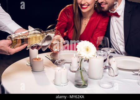 cropped view of waiter pouring wine while couple having romantic date in restaurant Stock Photo