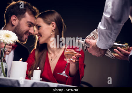 waiter pouring wine while smiling couple having romantic date in restaurant on valentines day Stock Photo