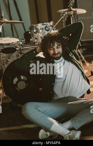 happy bearded drummer relaxign while leaning back on drum set Stock Photo