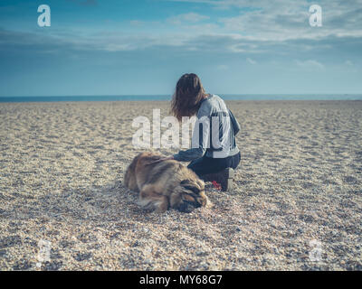 A young woman is sitting on the beach with her big Leonberger dog Stock Photo