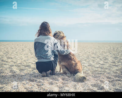 A young woman is sitting on the beach with her big Leonberger dog Stock Photo