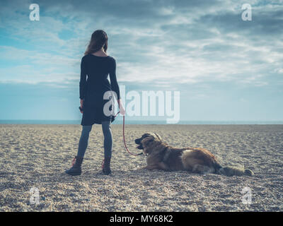 A young woman is on the beach in the autumn with her giant Leonberger dog Stock Photo