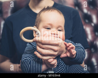 A mother is offering her baby a teething ring to chew on Stock Photo