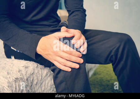 Young man suffering from leg pain at home. tendonitis inflammation of the ligaments. Stock Photo
