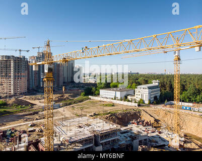yellow building cranes on construction site against blue sky background Stock Photo