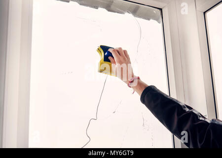 Window cleaner using a squeegee to wash a window. Washing the window with a magnetic brush. Simultaneous cleaning of the window on both sides. Stock Photo