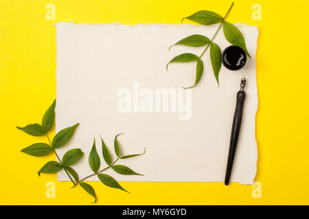 Blank artist sheet on bright yellow background with calligraphy pen and ink. View from the top. Artistic mockup template for your design. Minimal summ Stock Photo