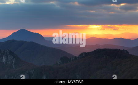 Dramatic sunset rays behind silhouette of of mountain Stock Photo