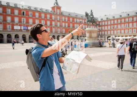 Hipster young man traveler traveling in Madrid holing up a map in the plaza major in tourist travel europe concept Stock Photo
