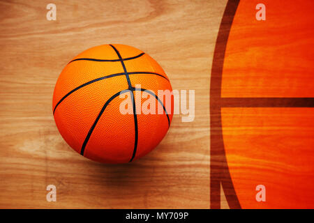 Basketball ball laying on hardwood court floor, top view Stock Photo