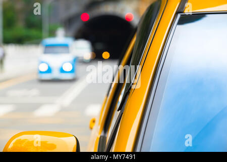 Closeup front window of yellow car and blurred traffic behind at one way road out of dark tunnel Stock Photo