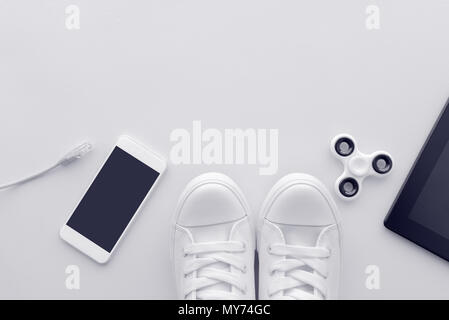 Millennial generation gadgets flat lay top view with copy space - minimalistic composition in pale white pastel tones including smartphone, computer n Stock Photo