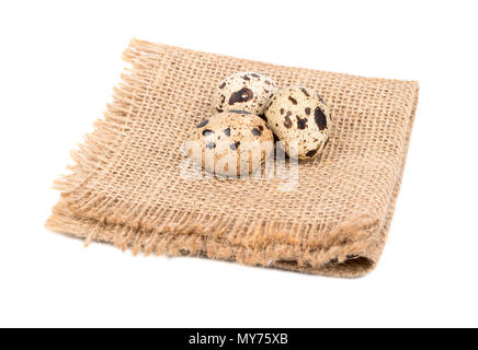 Three raw quail eggs on the burlap and white background Stock Photo